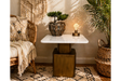 Square side table with white marble top and bronze metal base in cozy room setting, shown from front angle.