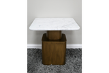 Square side table with white marble top and bronze metal base on gray shag carpet, front view.