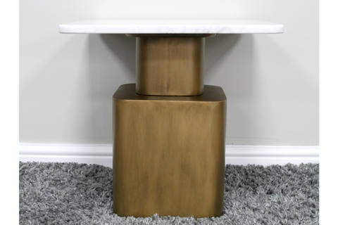 Side table with white marble top and gold rectangular base, photographed from front on gray carpet background.