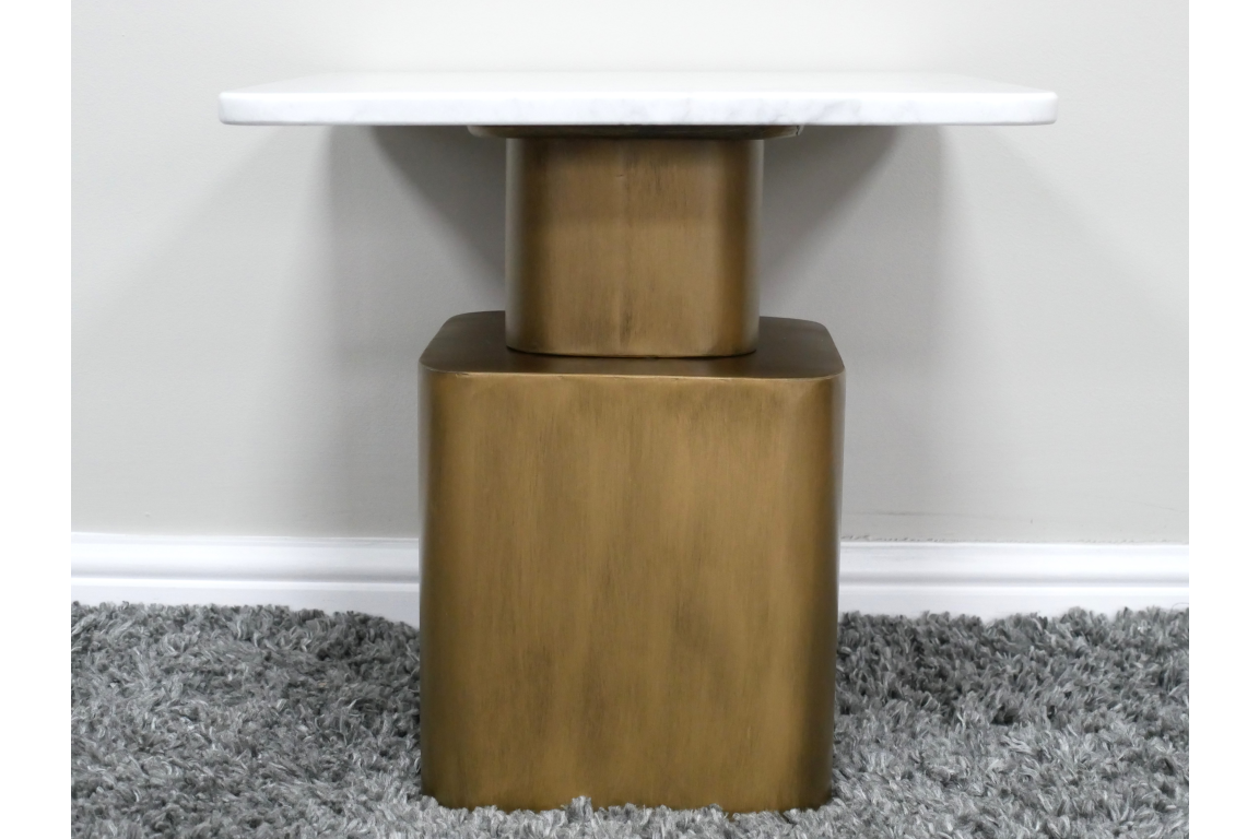 Side table with white marble top and gold rectangular base, photographed from front on gray carpet background.