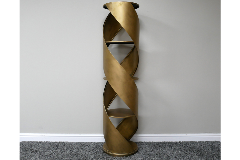 Tall swirl display cabinet in bronze metal with spiral design and three shelves, standing against a plain wall on gray