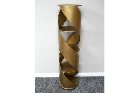 Tall spiral display cabinet in brass-colored metal with circular shelves, shown from front angle against white wall.