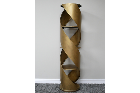 Tall gold metal display cabinet with spiral design and three shelves, shown from front on grey carpet background.