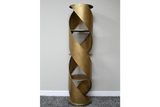 Tall gold metal display cabinet with spiral design and three shelves, shown from front on grey carpet background.