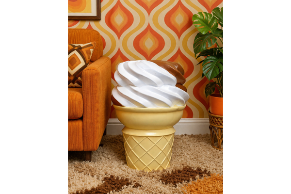 Ice Cream Side Table shaped like a vanilla and chocolate swirl ice cream cone, beside orange sofa in retro room.
