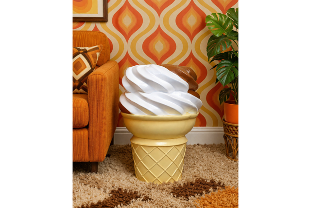 Ice Cream Side Table shaped like a vanilla and chocolate swirl ice cream cone, beside orange sofa in retro room.