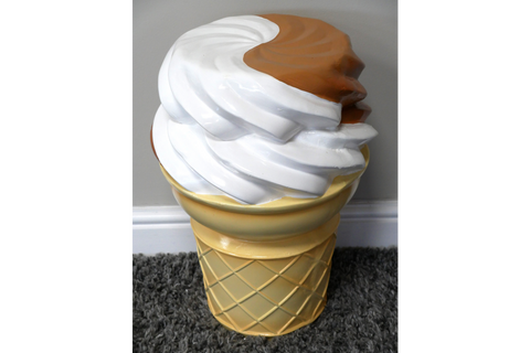 Plastic ice cream cone-shaped side table in beige, white, and brown, shown from a high front angle on carpet.