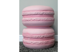 Pink macaron-shaped side table with textured detailing, photographed from front on a gray carpet floor against pale wall.