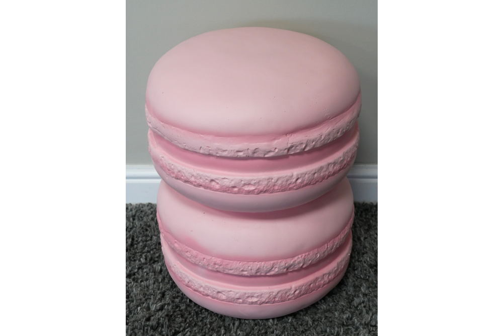 Pink macaron-shaped side table with textured edges, shown from an angled top view on gray carpet.
