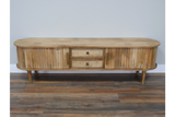 Wooden TV cabinet with rounded edges, slatted doors, woven drawer fronts, tapered legs, and natural finish.