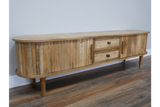 Wooden TV cabinet with rounded edges, vertical slat detailing, two woven drawer fronts, angled front view on wooden floor.