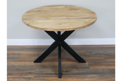 Round dining table with natural wood top and black metal X-shaped base, front view on wooden floor