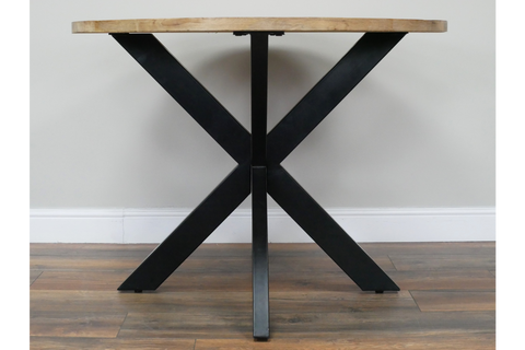 Round dining table with light wood top and black metal X-shaped base, front view on wooden floor.