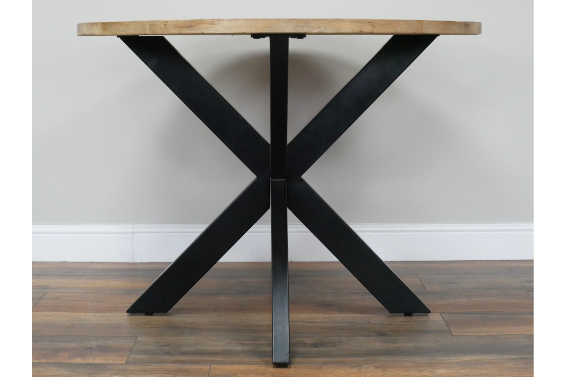 Round dining table with light wood top and black metal X-shaped base, front view on wooden floor.