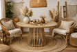 Round wooden dining table with slated base, natural finish, styled in boho room with rattan chairs and decor.