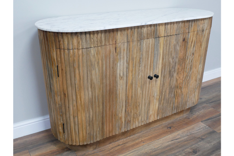 Wooden sideboard with vertical slats and white marble top, shown angled on a wooden floor against a pale wall.