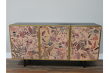 Large three-door cabinet with black top, gold frame, and textured leaf-patterned front panels, shown from front.