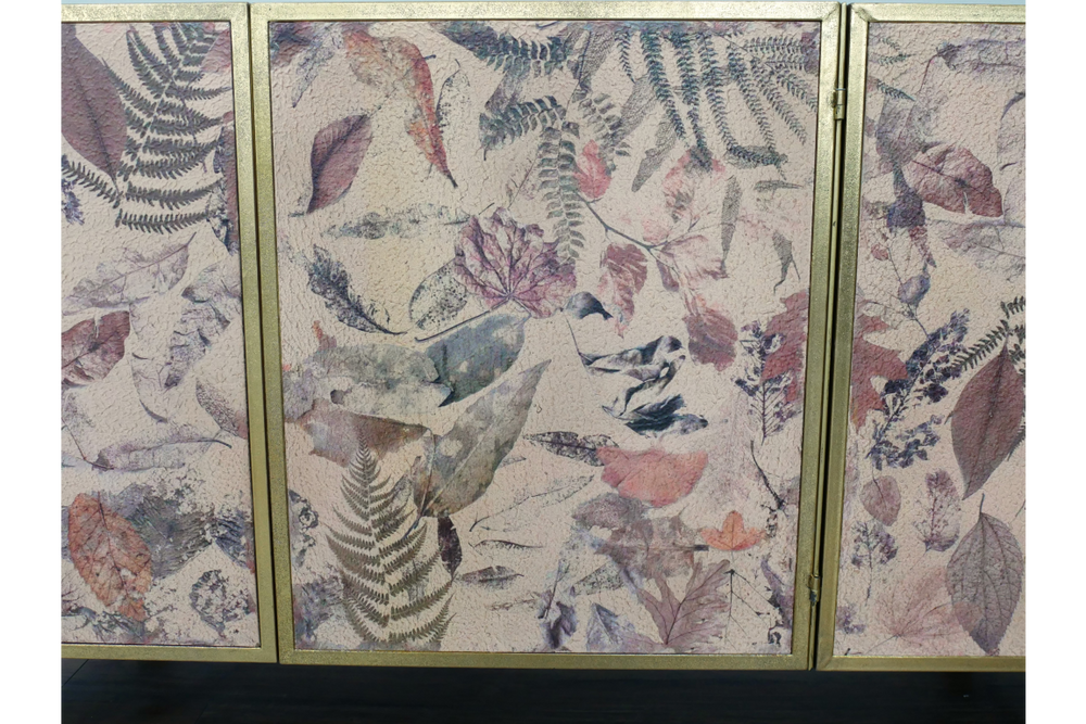 Large cabinet with three doors, gold frame, and multi-colored leaf pattern on textured surface, front view.