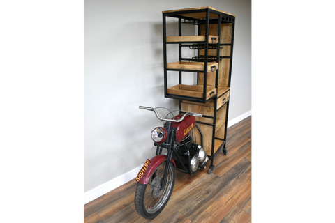 Industrial style motorbike bar cabinet with black metal frame and wooden shelves on hardwood floor, angled view.