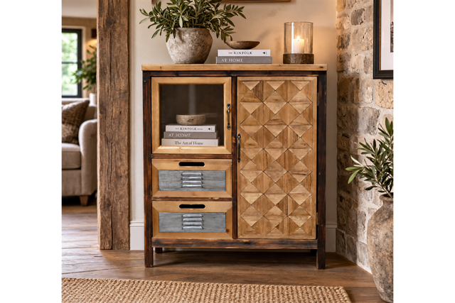 The rustic cabinet features a wooden frame with a geometric patterned door, a glass display section, and two gray drawers, perfect for stylish storage