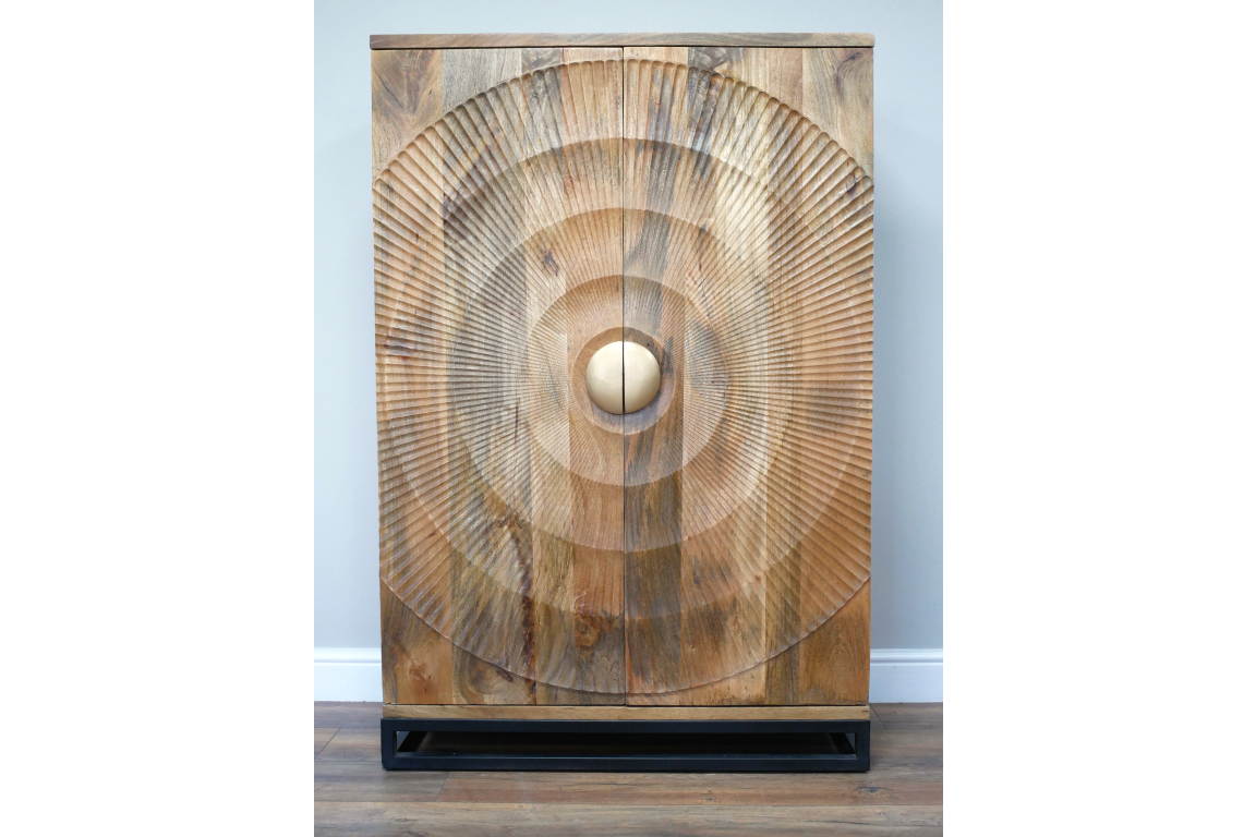 The Solstice Wine Cabinet features a natural wood finish with a striking circular textured design on the front and a round wooden knob, resting on a sleek black base