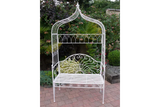 White metal garden bench with decorative arch and scrollwork on patio