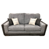 Grey fabric sofa with studded trim, quilted armrests, and four scatter cushions