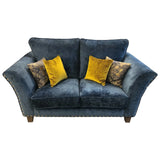 Dark blue velvet sofa with studded arms and four yellow and patterned accent cushions