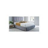 Grey upholstered bed frame with high headboard, white mattress, and bedside table