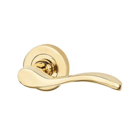 Polished brass wave-shaped lever door handle on a round rose, close-up
