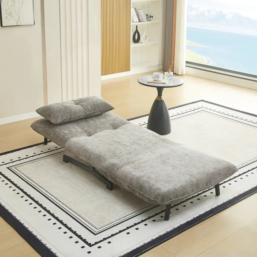 Grey single sofa bed with cushion in open position on modern rug near round side table