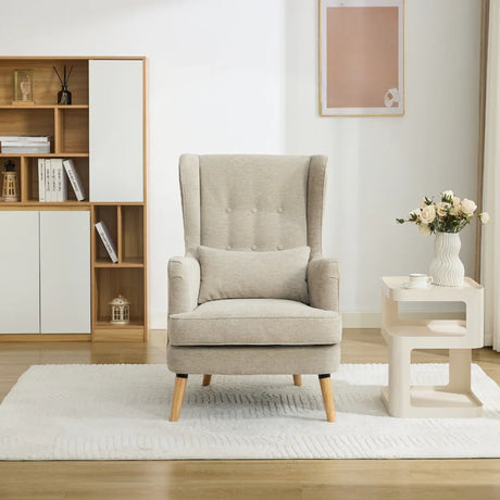 Beige wing chair with pillow set on white rug beside modern side table and bookshelf