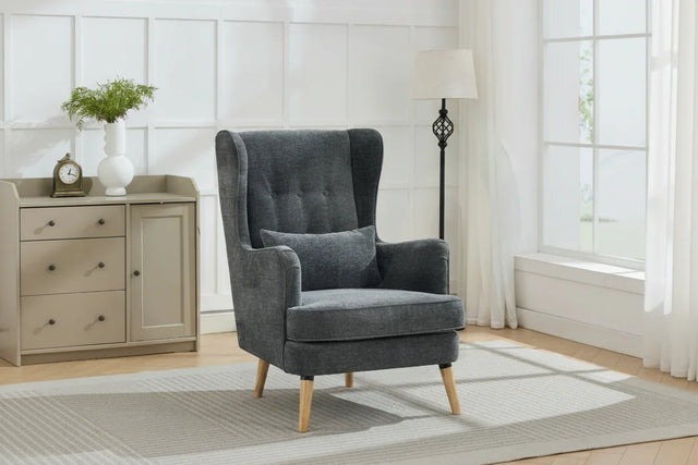 Dark grey wingback chair with cushion and wooden legs in a bright living room corner