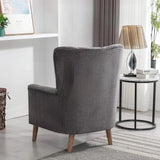 Graphite armchair with wooden legs in living room beside round side table and lamp