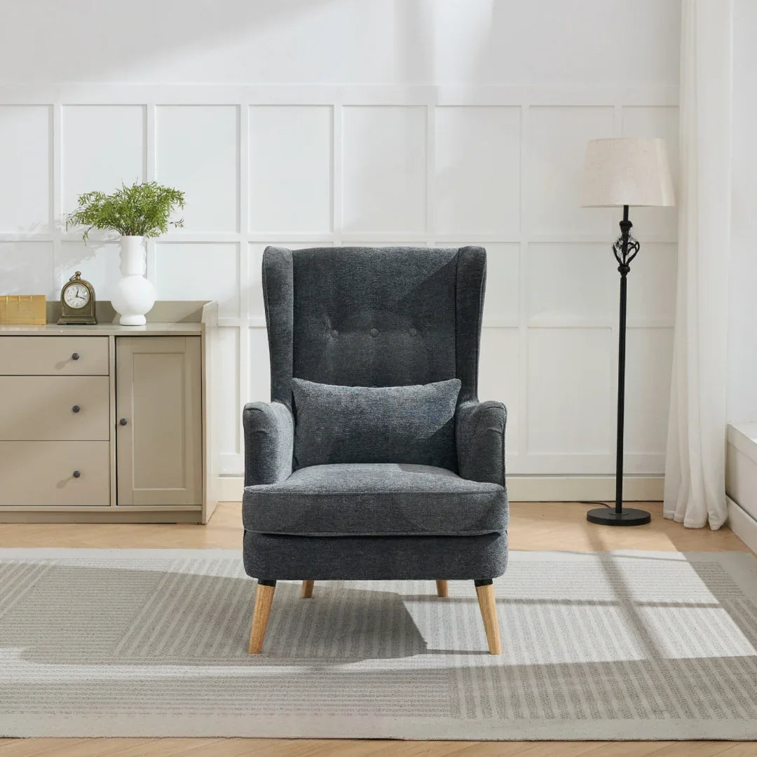 Dark grey wing chair with cushion and wooden legs on light rug in bright living room