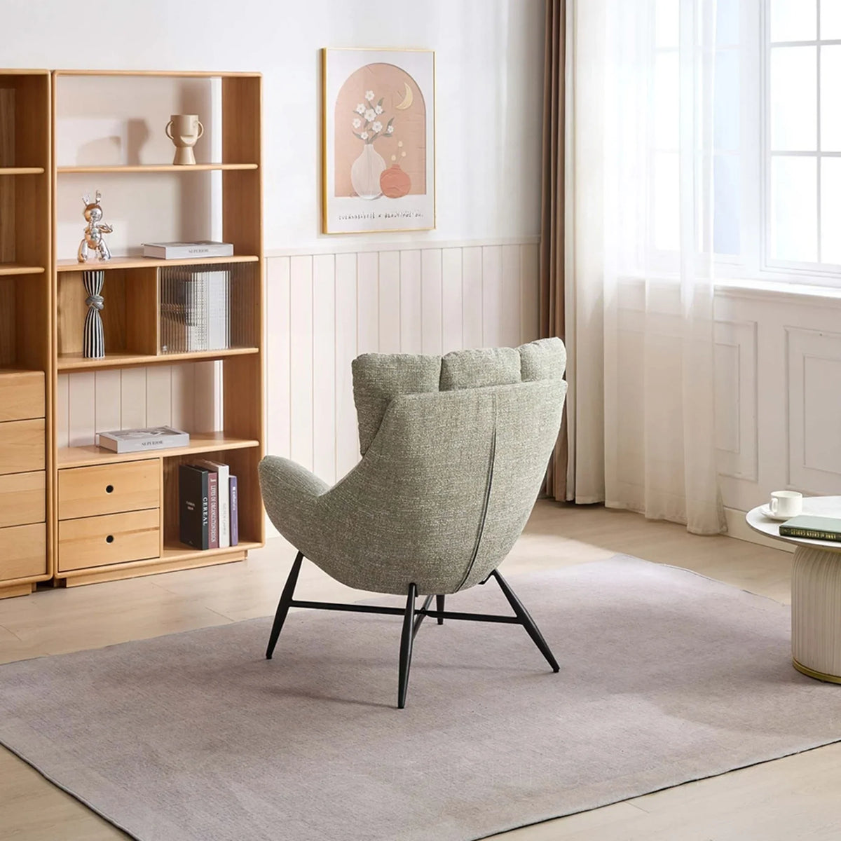 Green accent chair with black legs in modern living room, bookshelf and table nearby