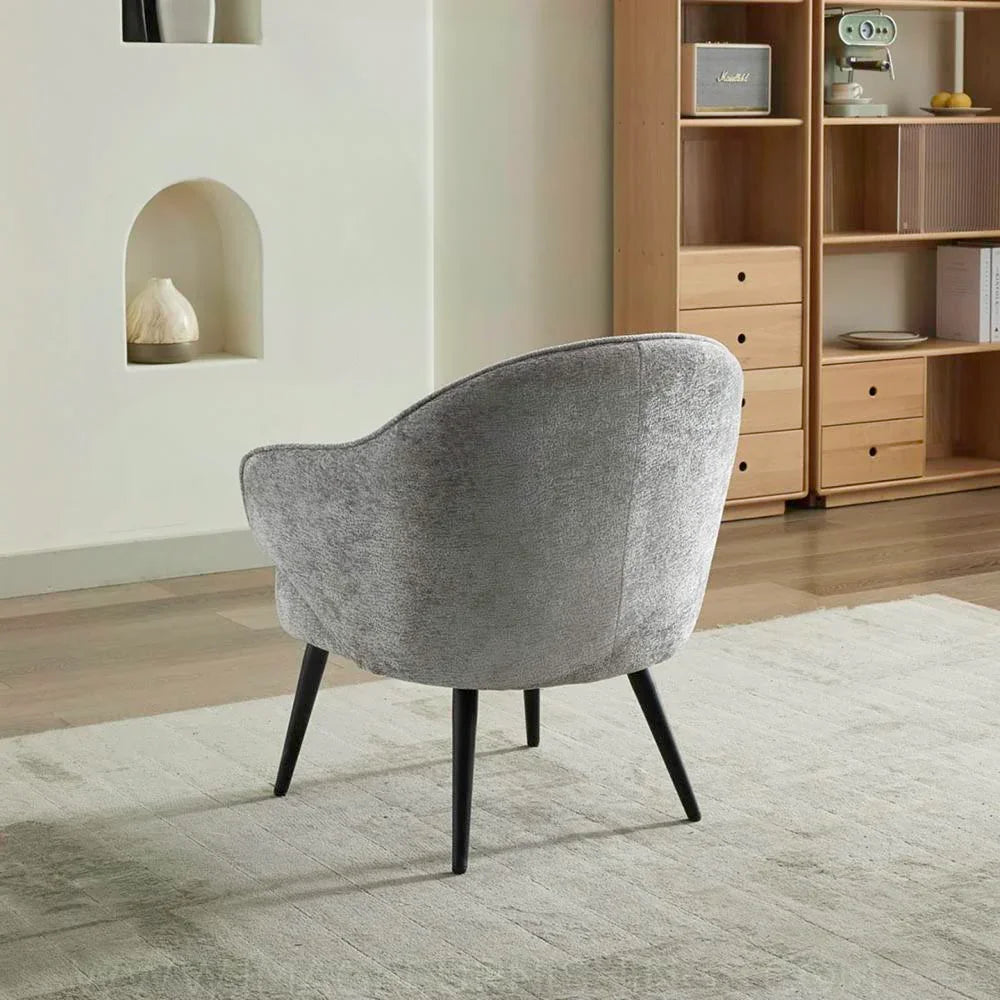 Light grey accent chair with curved back and black legs on neutral rug