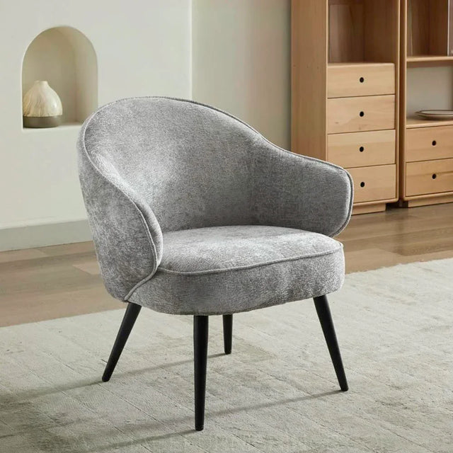 Light grey accent chair with curved backrest and black legs on a textured rug
