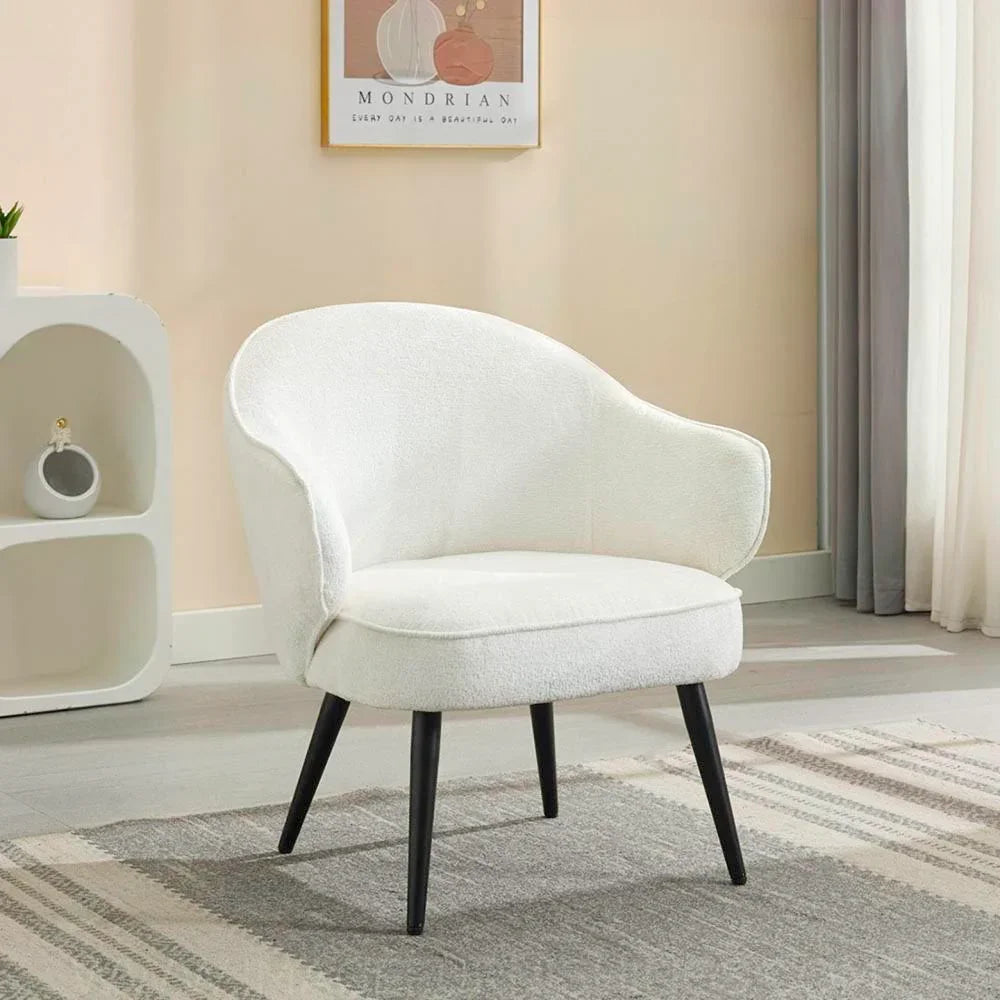 Cream accent chair with curved backrest and black wooden legs on grey patterned rug