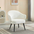 Cream accent chair with curved backrest and black wooden legs on grey patterned rug