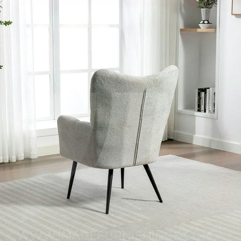 Light grey accent chair with black legs positioned on a striped rug near window