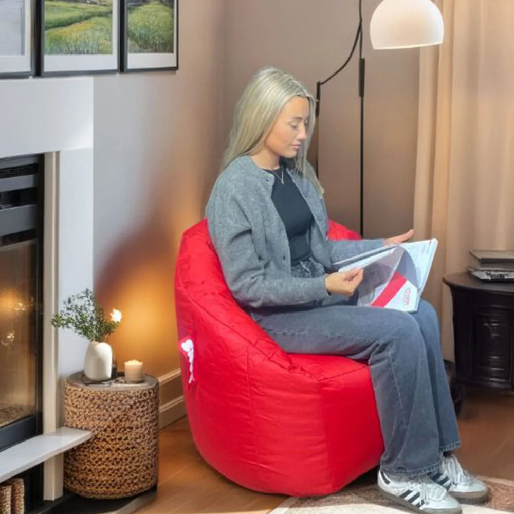 Red bean bag chair in living room with woman reading a magazine