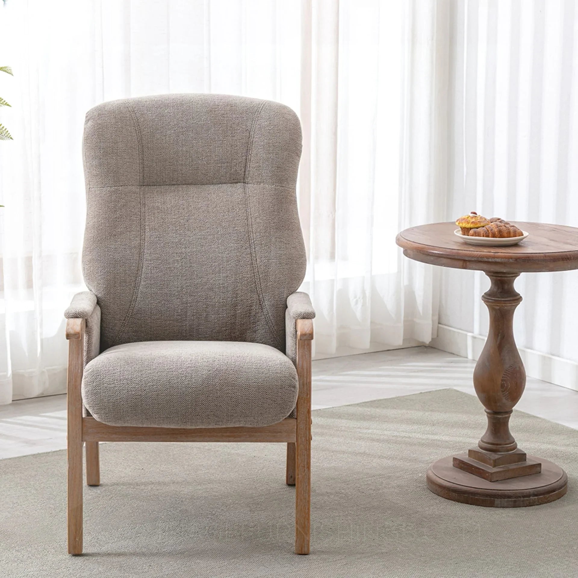 Oatmeal armchair with wooden legs beside round wooden side table in bright living room