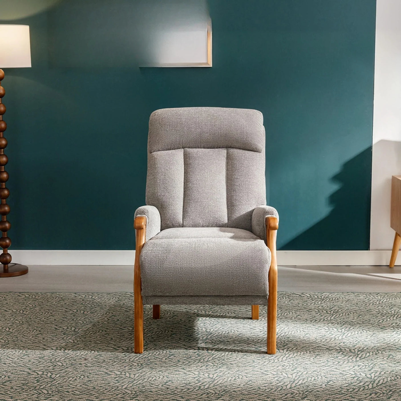Silver fireside chair with wooden arms and legs on patterned rug in modern living room
