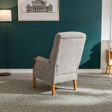 Silver fireside chair with wooden legs shown from the back in a modern living room