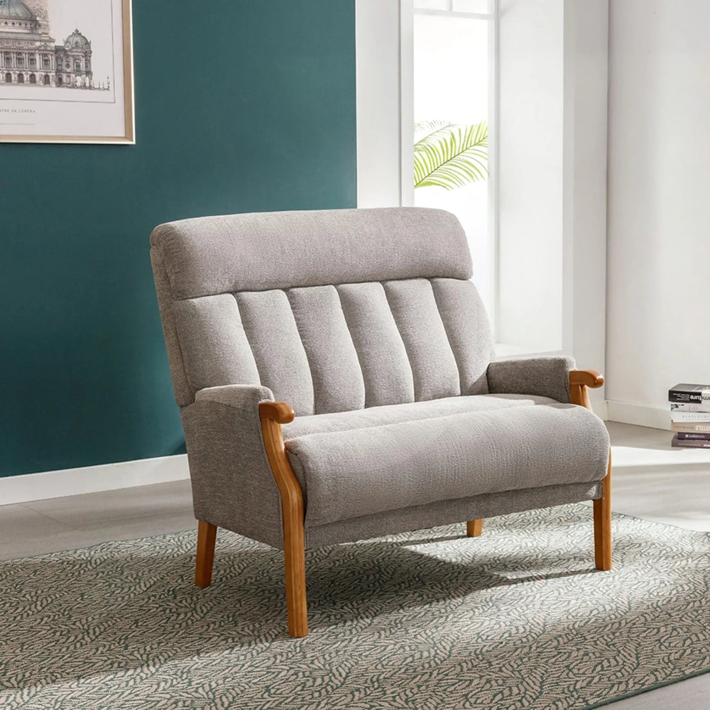 Silver fireside loveseat with wooden arms and legs on patterned rug in bright room