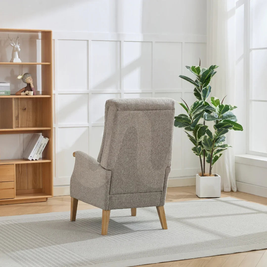 Beige thistle chair with wooden legs in bright living room with bookshelf and potted plant