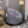 Grey fabric bean bag chair in living room with lamp and textured side table