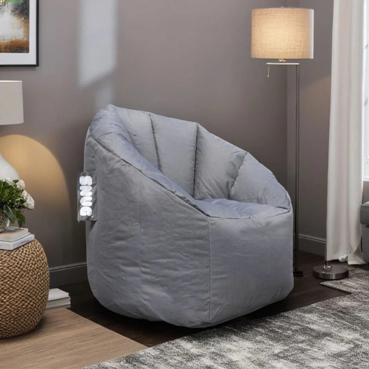 Grey fabric bean bag chair in living room with lamp and textured side table