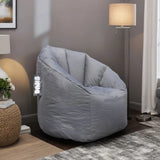Grey fabric bean bag chair in living room with lamp and textured side table